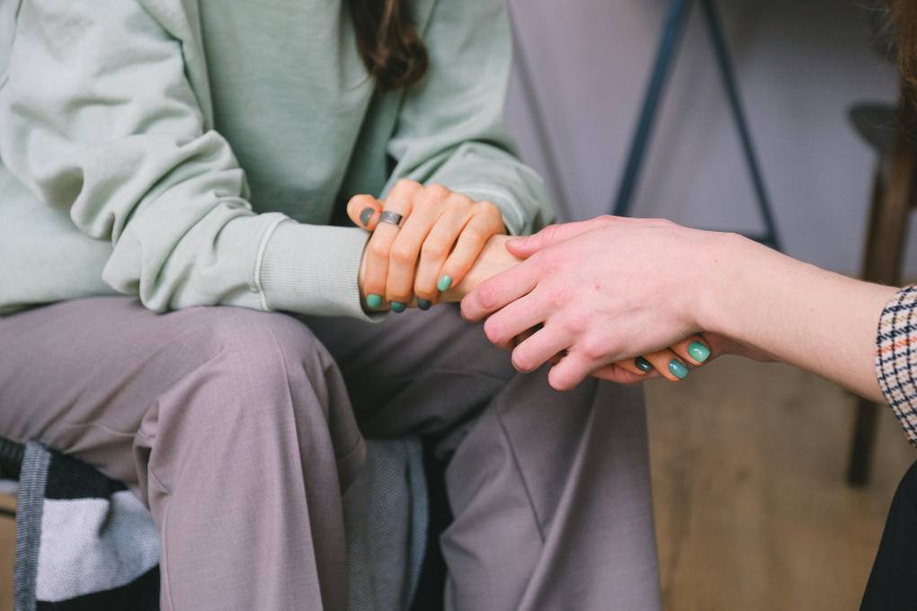 A close-up photo of one person holding another's hand to comfort them.