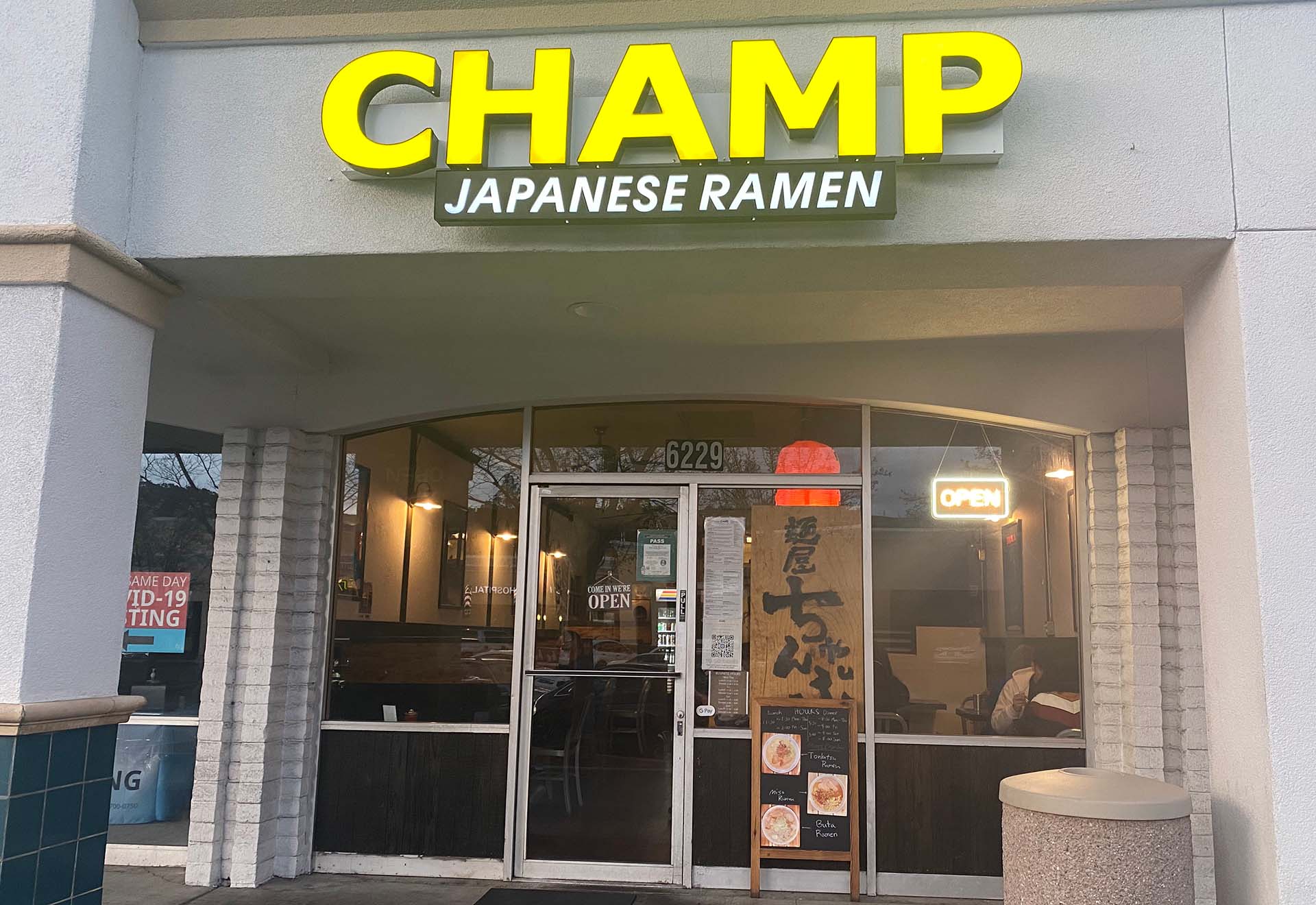 Exterior of a ramen restaurant. The sign reads "CHAMP" in bold yellow lettering, with "Japanese Ramen" in white underneath.