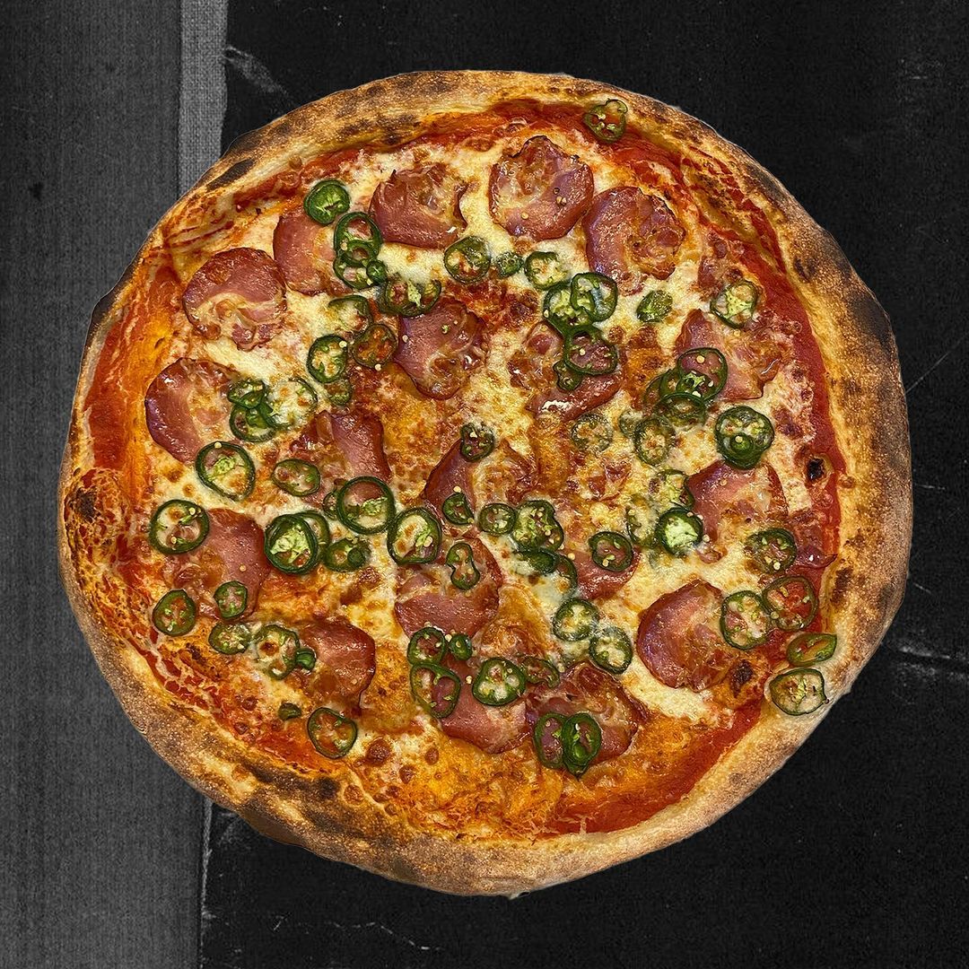 Overhead view of a pizza topped with hot coppa and jalapeños. 