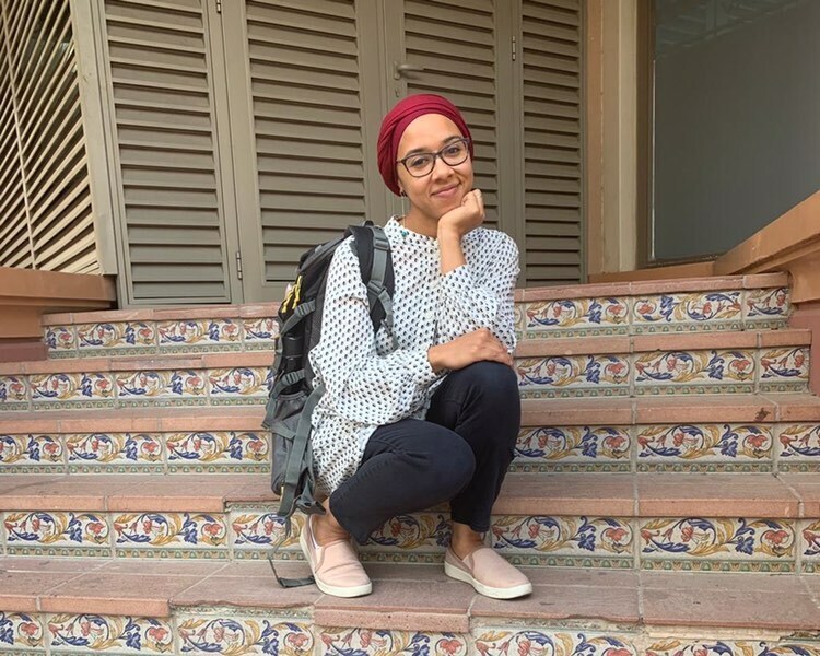 Aïdah Rasheed sits on a set of steps while posing for a photo.