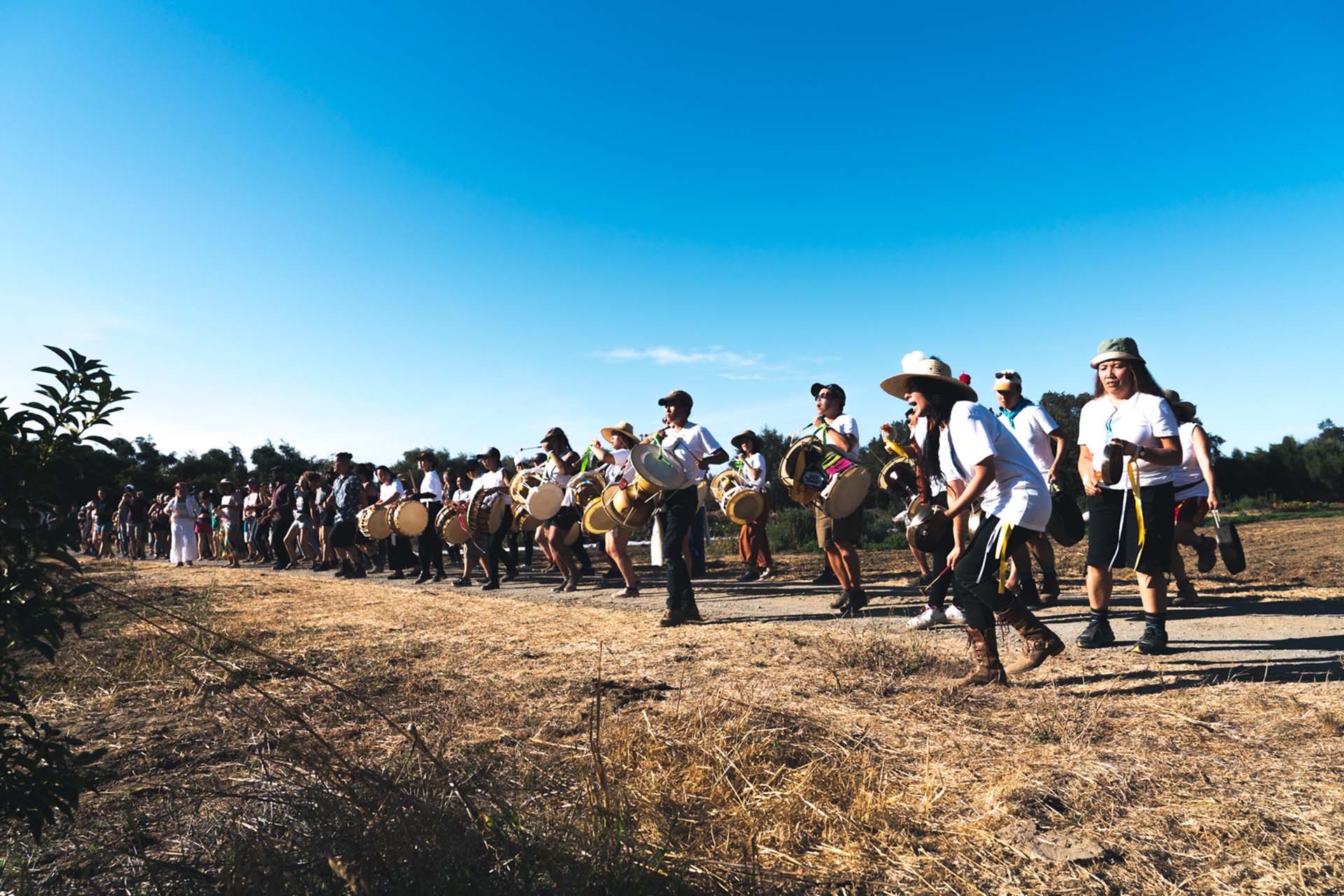 A line of traditional Korean drummers perform a ceremony in an open field.