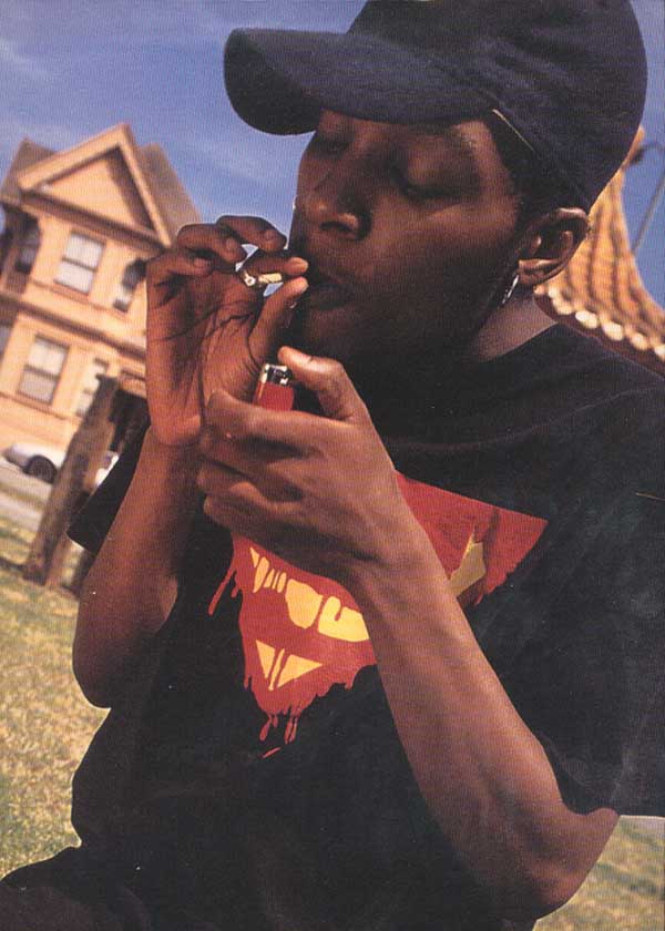 a young man in a superman t-shirt smokes in a park