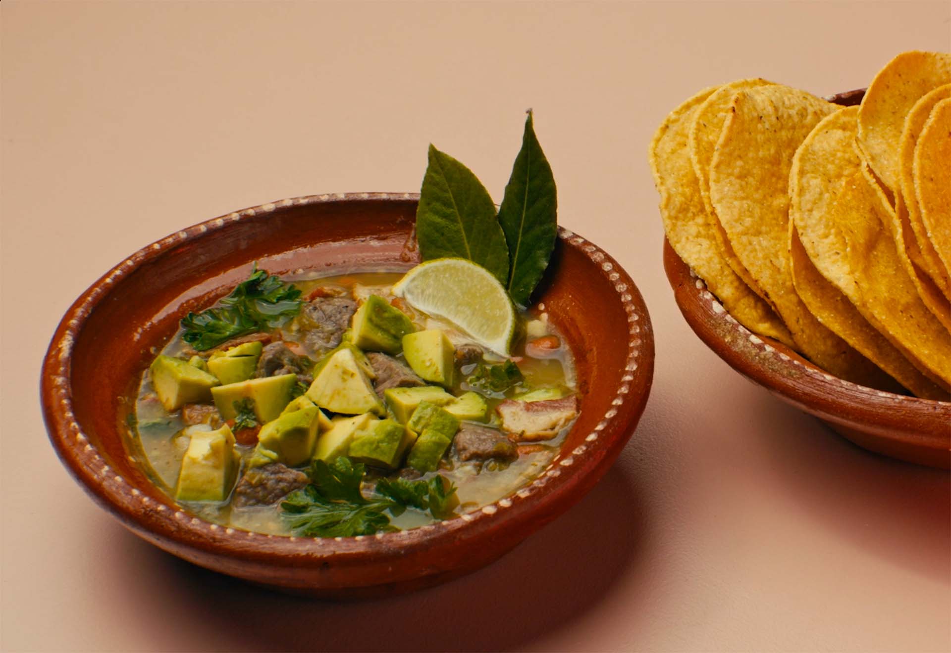A stew made with bacon, onion, beans and avocado, served with a bowl of tostadas on the side.