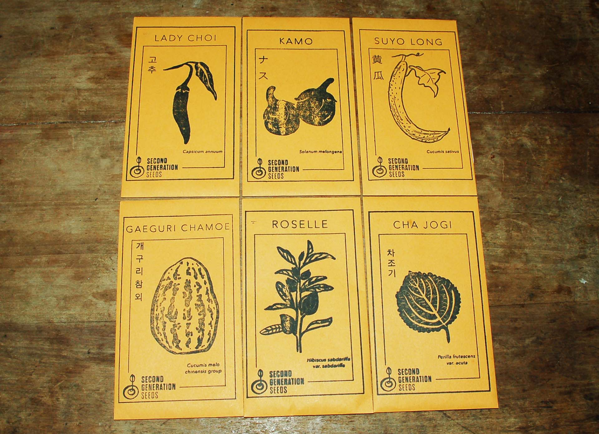 Packets of Asian vegetable seeds decorated with illustrations of each corresponding vegetable: lady choi, kamo, suyo long, gaeguri chamoe, roselle and cha jogi.