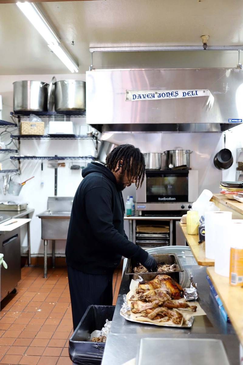 an employee at Davey Jones Deli prepares a whole roasted turkey