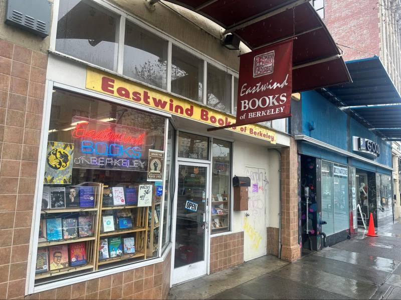 The Eastwind Books storefront in Berkeley has big, glass windows with shelves full of books.