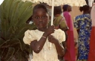 an old photo of a young Black girl wearing a white dress carrying a parasol
