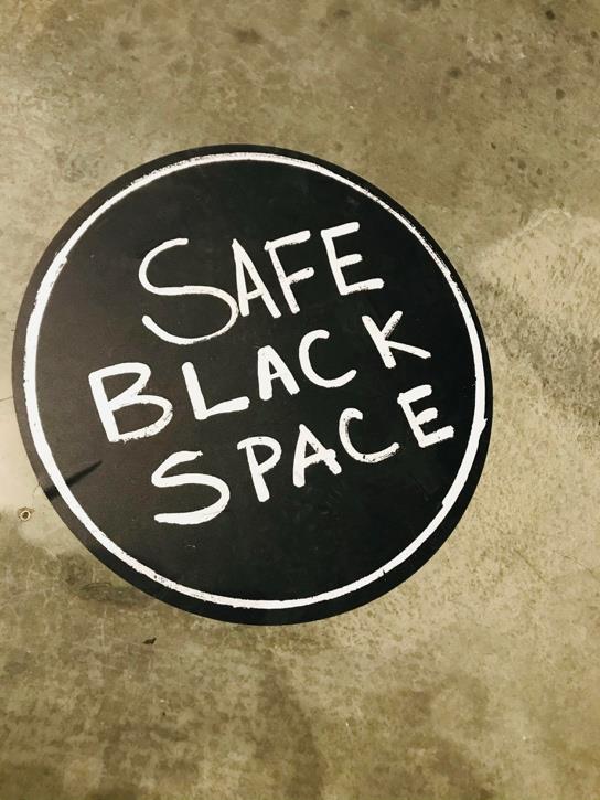 A black circle with white text on concrete floor that reads "SAFE BLACK SPACE"