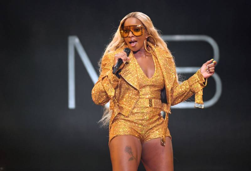 Mary J. Blige sings into the mic while wearing a head-to-toe gold sequins outfit. 