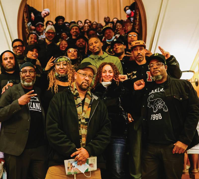 A large group of hip-hop artists and cultural practitioners in their 40s and 50s stands in a stairwell of a library.