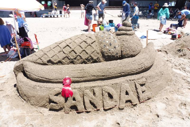 a giant sand castle shaped like an ice cream sundae, with the word 'sandae'