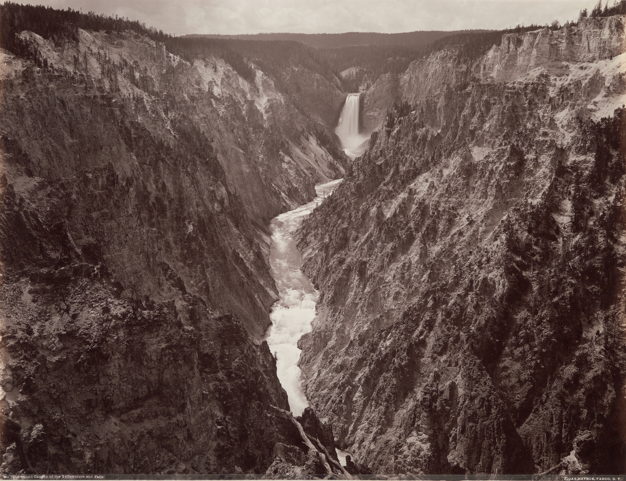 Sepia toned photograph of rushing river between two high mountainous walls