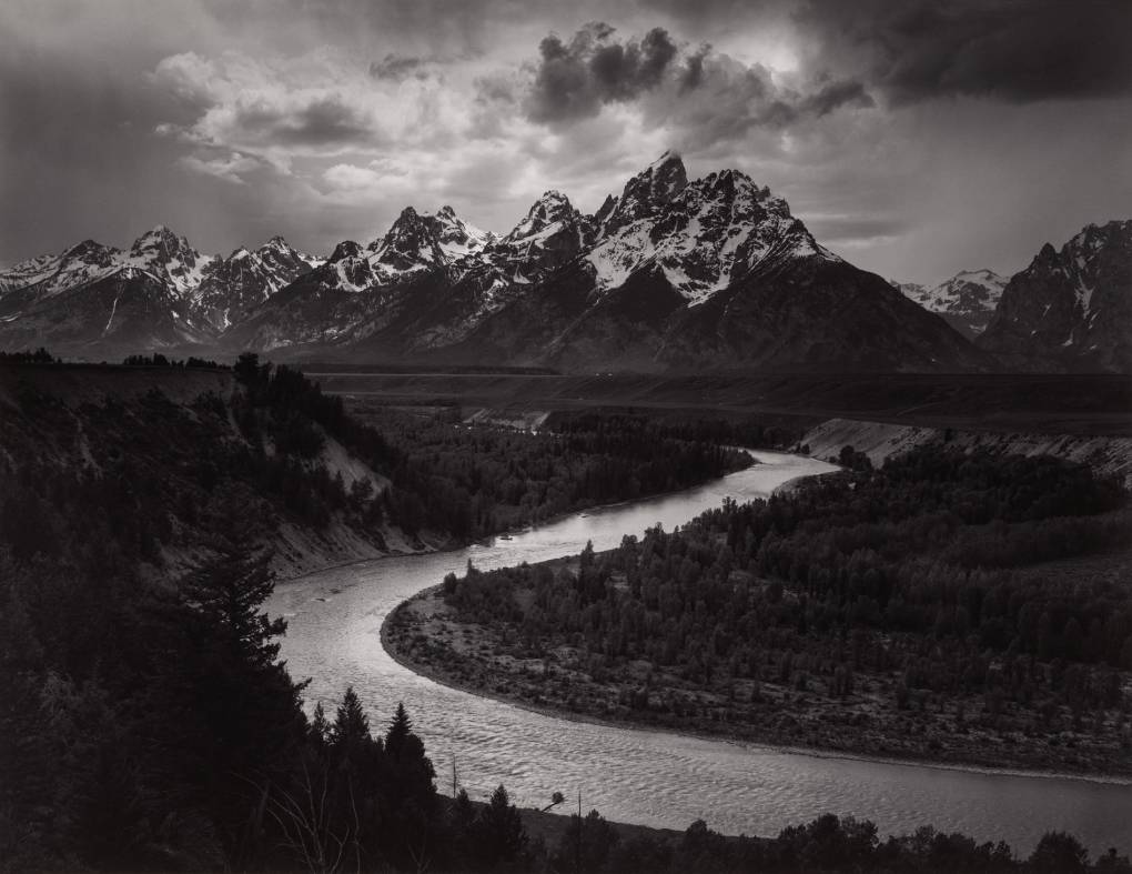 Black-and-white photo of dramatically lit mountain with curving river in foreground