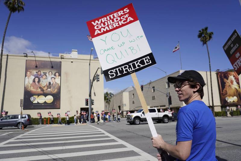 A Writers Guild of America striker holds up a sign that says: "You came up with Quibi."