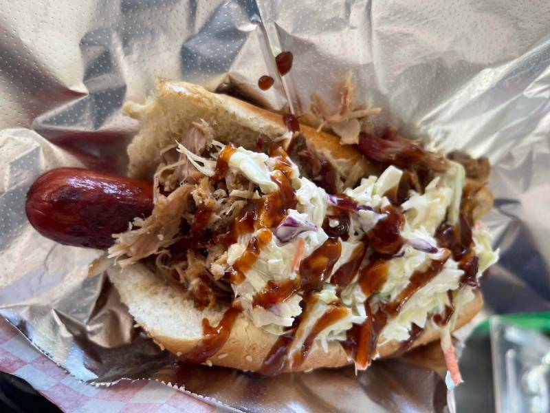 a photo of "the Big Kahuna" which consists of a beef hot dog topped with pulled pork and island-style coleslaw