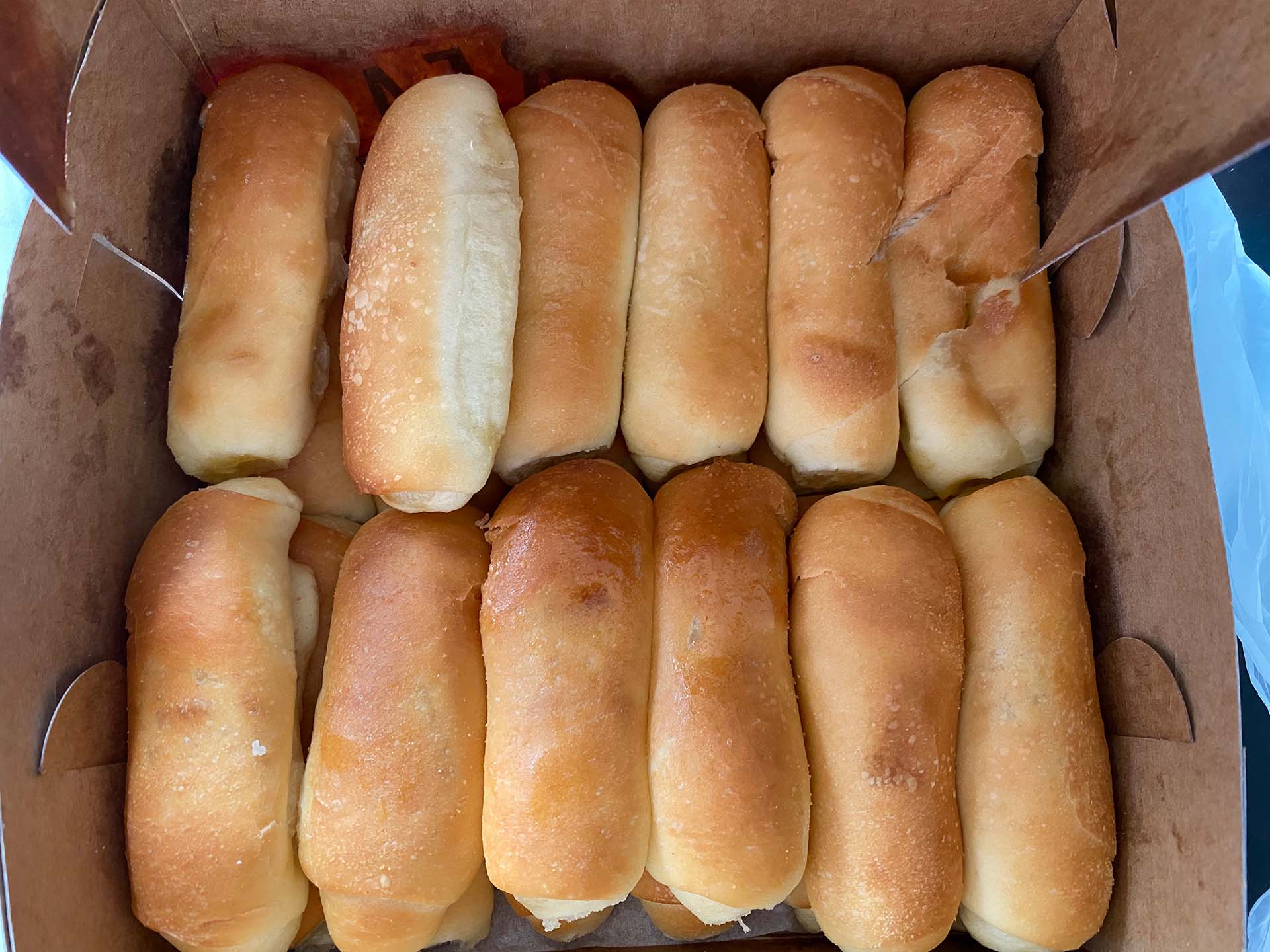 A box of señorita bread — more than 20 golden-brown rolls stacked inside.