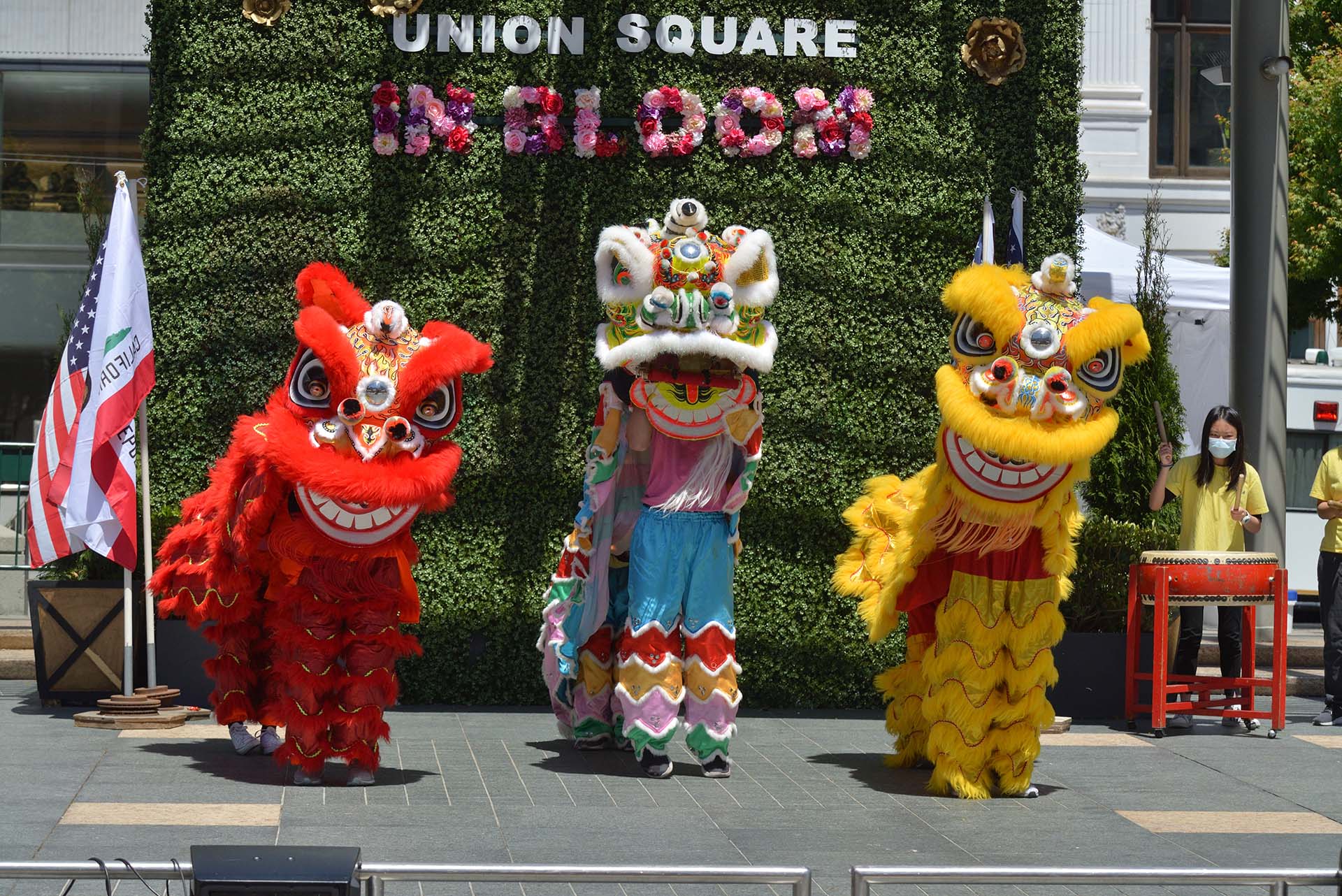 Three performers in colorful red and gold lion costumes perform a traditional lion dance.