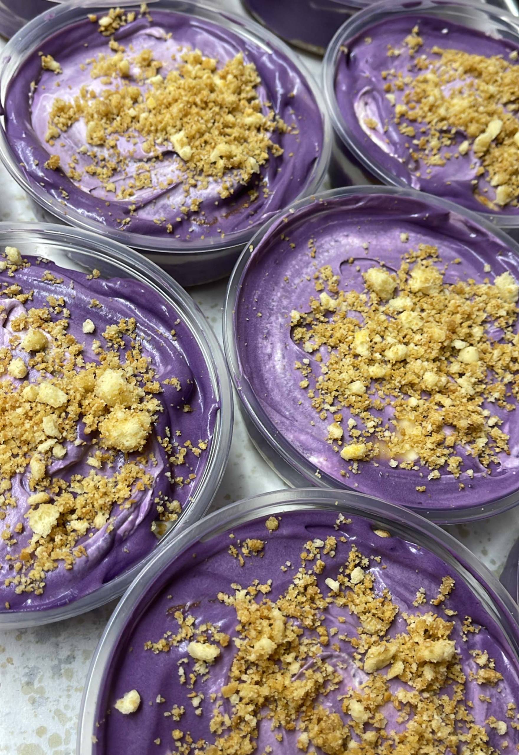 Small jars of purple banana-ube cream pudding, topped with crushed pistachios.