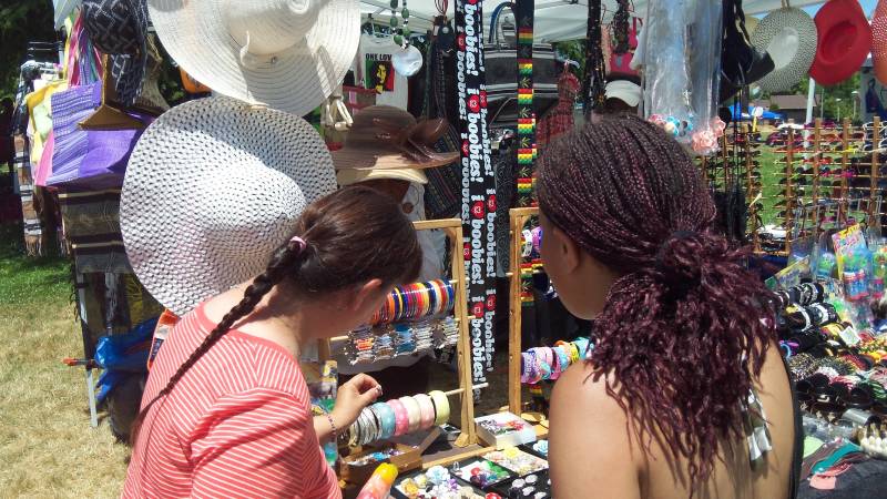 two people, seen from the back, look at bracelets at a vendor's stand