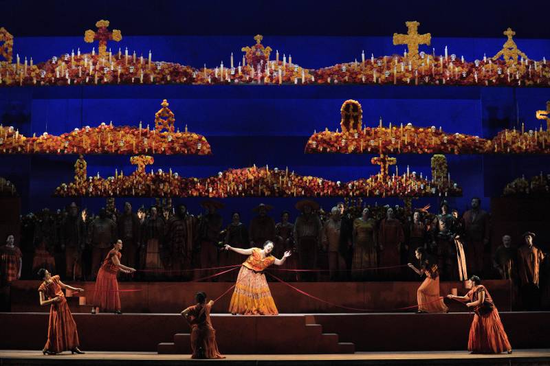 a blue and orange colorful stage with a woman in an orange dress dancing at center