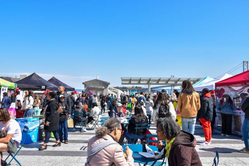 people at an outdoor farmers' market against a blue sky in San Francisco