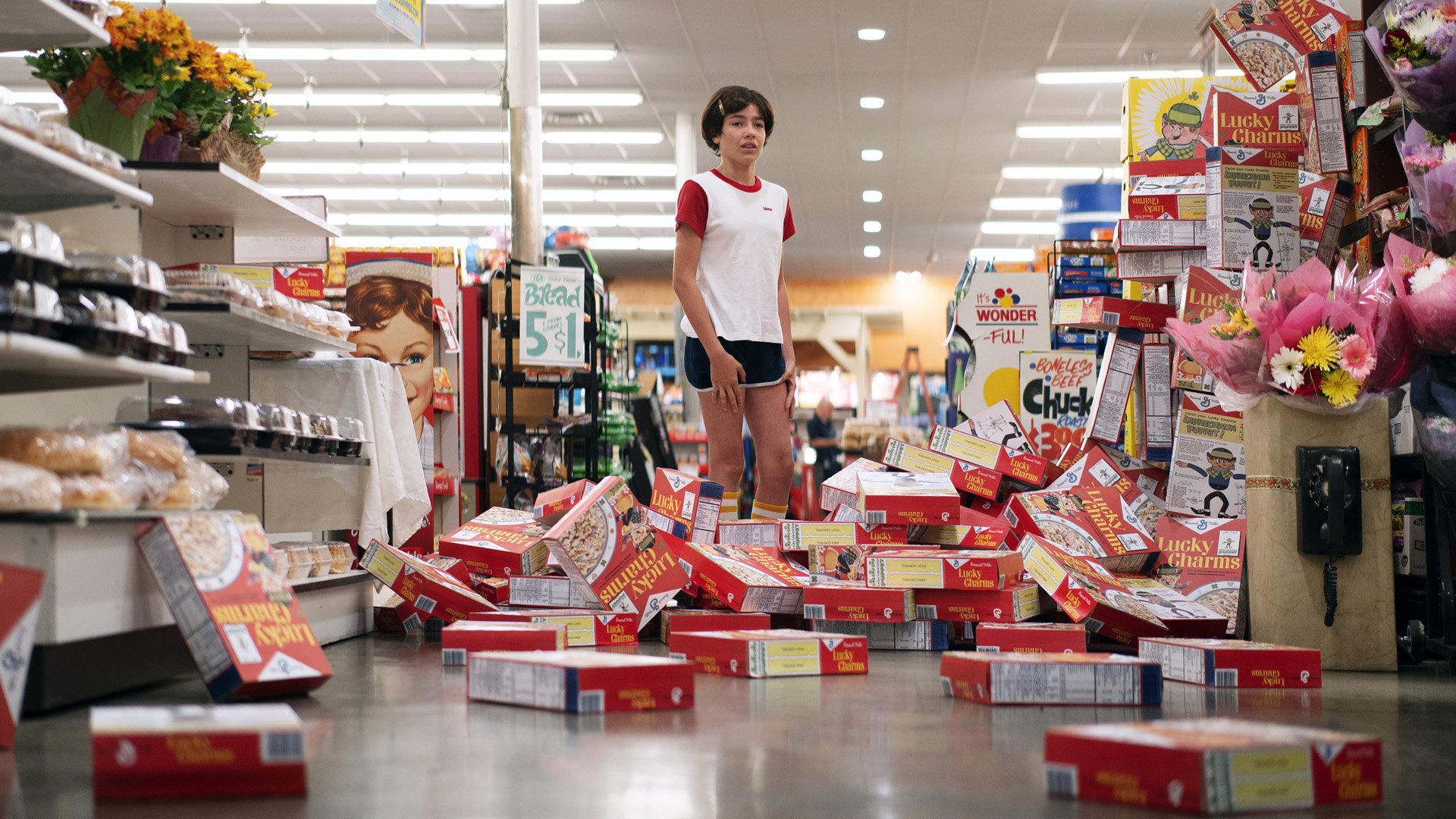 Photogrpahy of young girl in t-shirt and shorts looking at boxes of cereal fallen into a grocery aisle