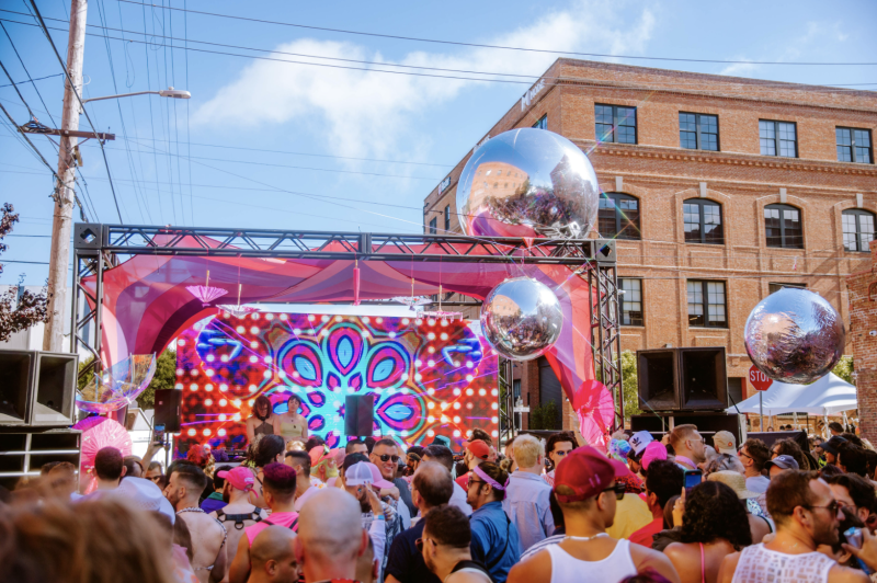 a large street party with a pink stage and a crowd of people dancing in front of it