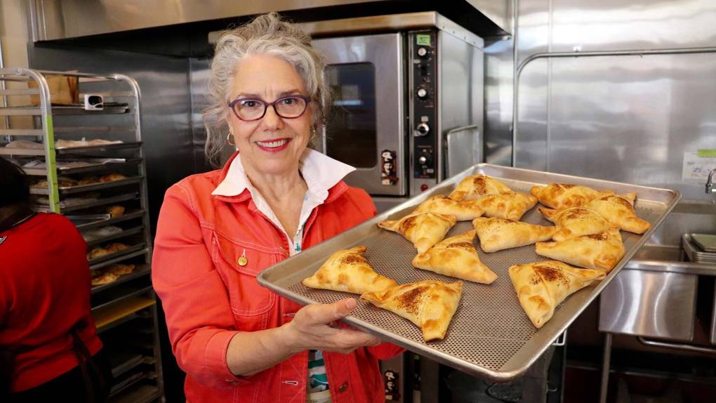 a Chilean foodmaker holds up a baking tray of empanadas inside Chile Lindo