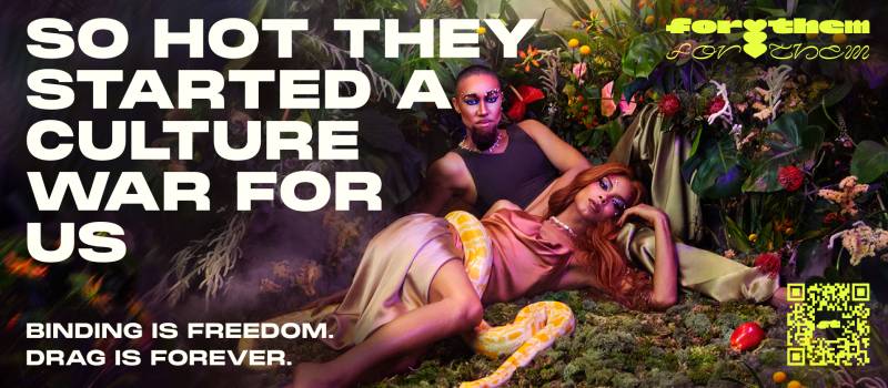 A drag king and queen recline together in a tropical green space. Next to them is the text: "So hot they started a culture war for us."