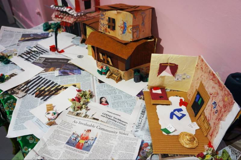 newspapers and postcards and other art materials on a table against a pink wall