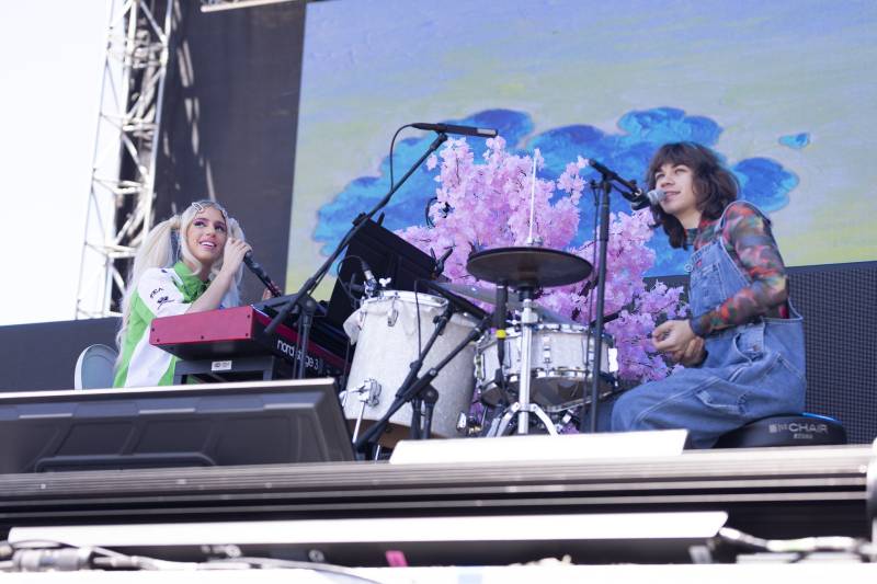 A young drummer and pianist perform in front of a purple and blue backdrop. 