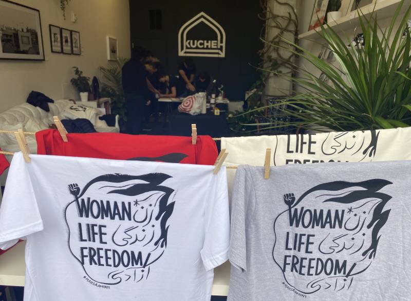 Shirts hang on a line with the words Woman, Life Freedom printed on them 