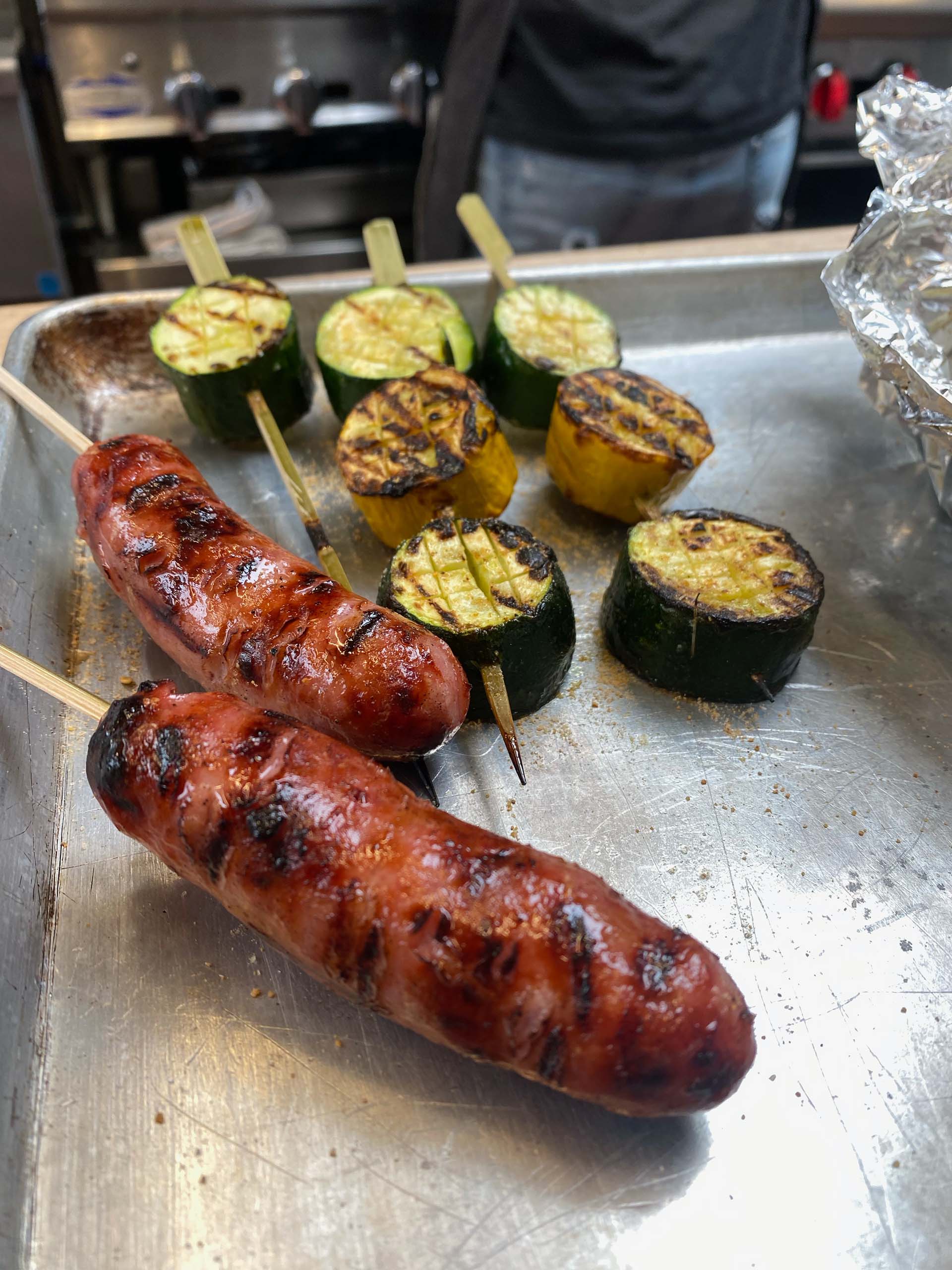 Skewers of zucchini and Taiwanese sausage in a metal tray.
