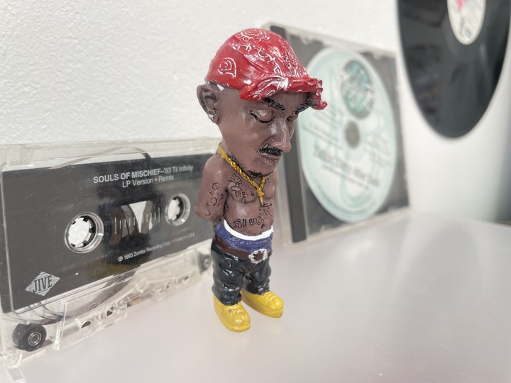 A mini Tupac figurine and a copy of Souls of Mischief's classic '93 Til Infinity on display. 