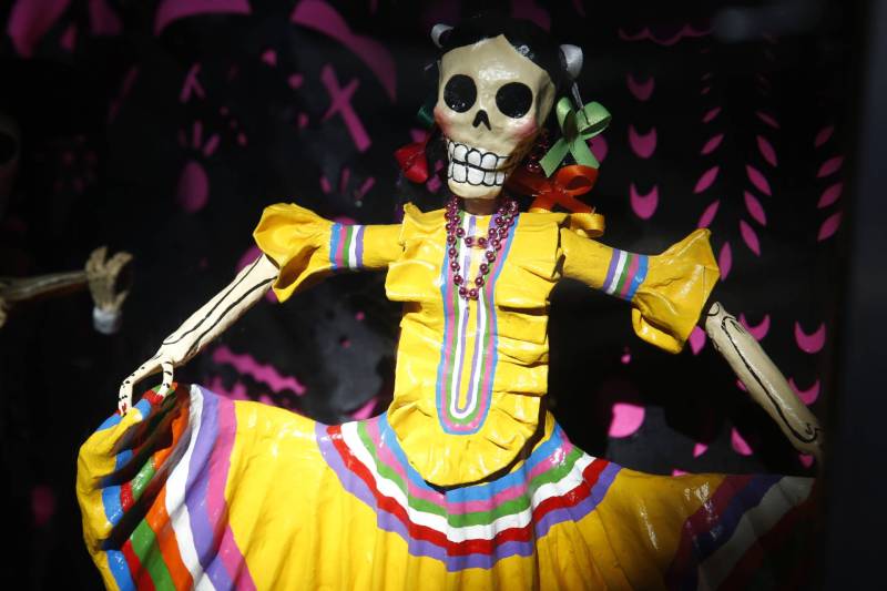 A Dia de los Muertos display including a skeleton woman dancing in a yellow dress.