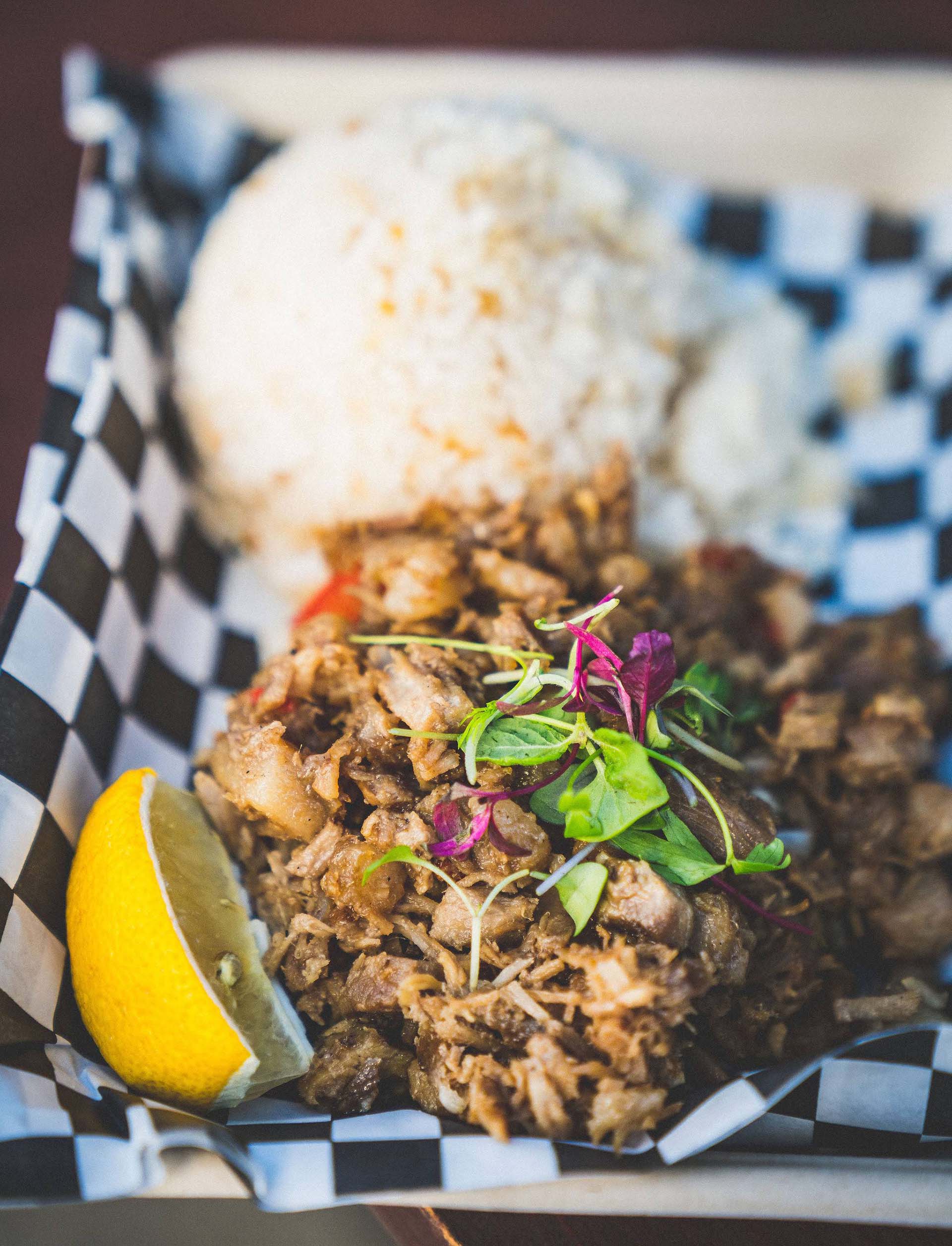 Pork sisig served with a slice of lemon and a mound of white rice.