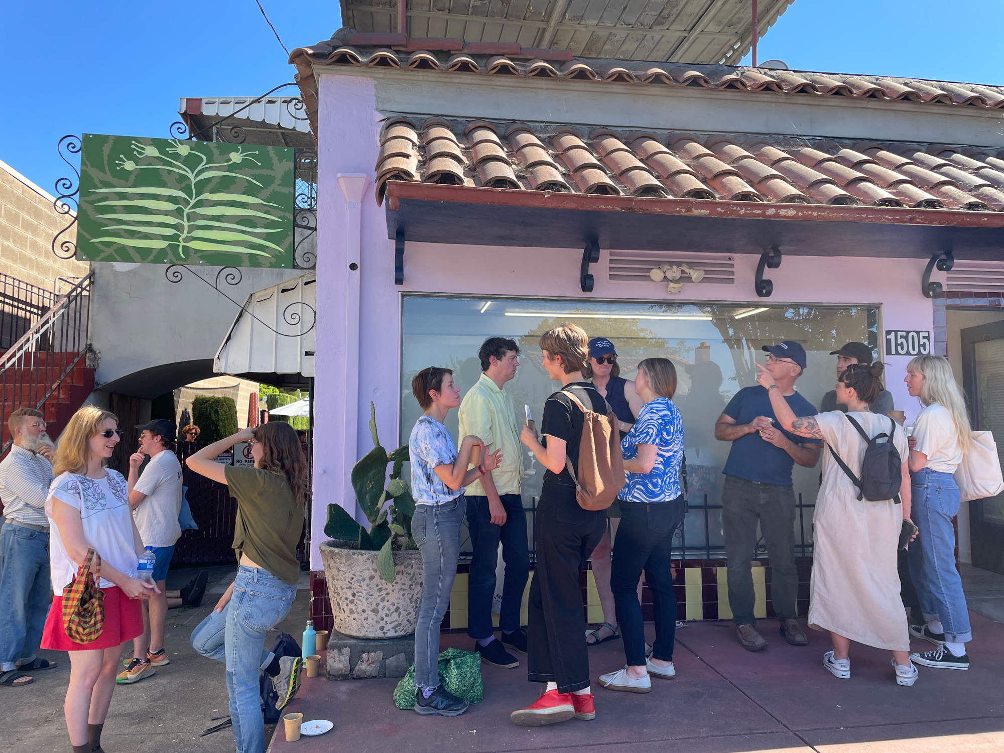 A crowd outside of a tile-roofed storefront on a sunny day