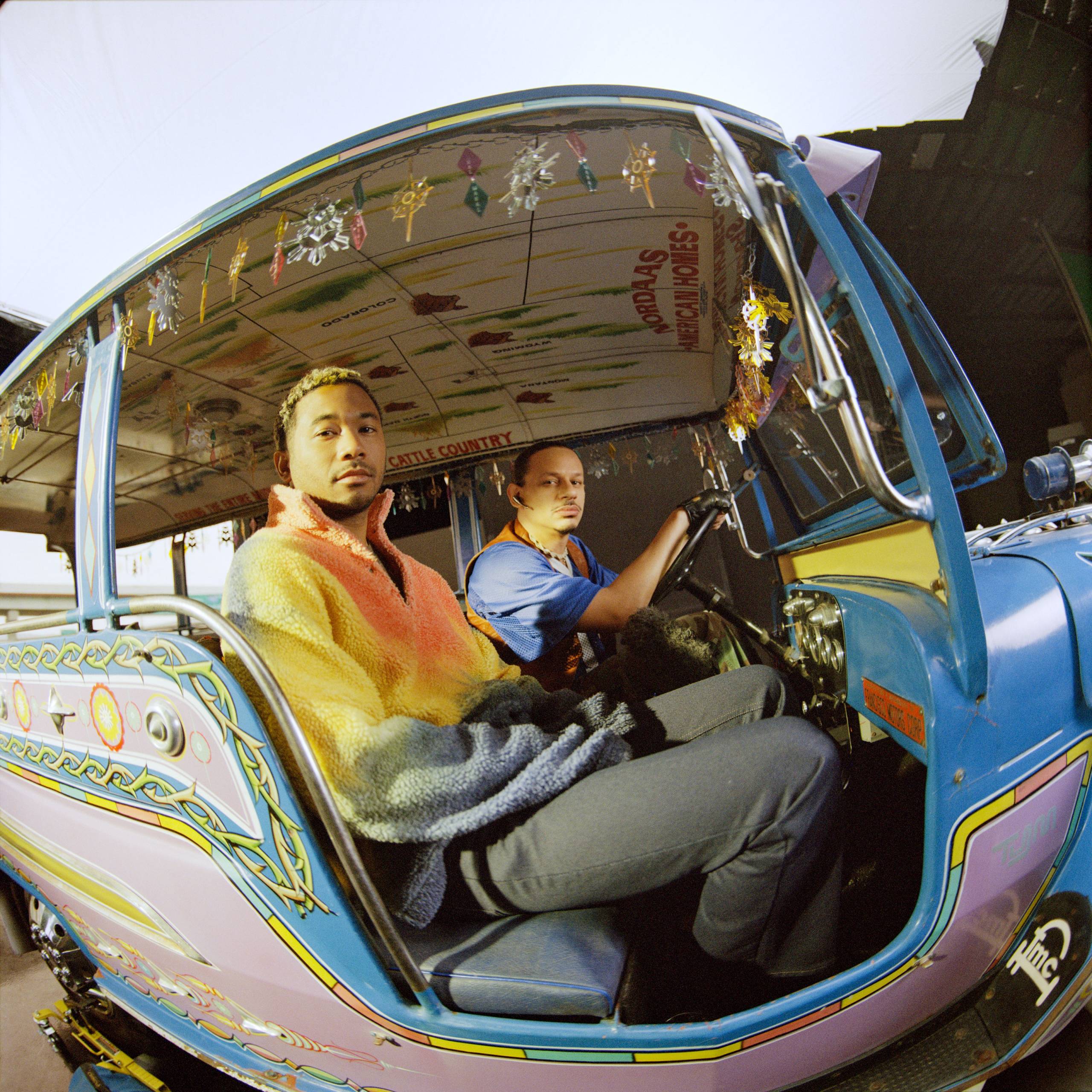 Two men in a decorated car, with a fisheye lens effect on the photo