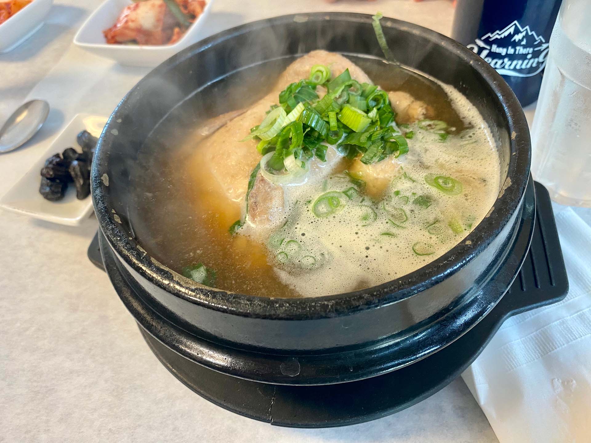 A steaming vessel of chicken ginseng soup with a whole cornish hen.