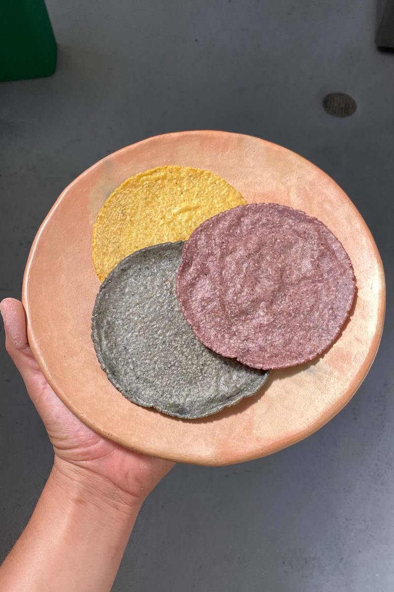 tri color tortillas (yellow, blue and purple) are displayed on a tan plate inside the Berkeley kitchen where they were made