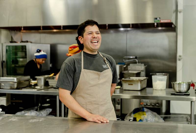 a Mexican American chef smiles inside the kitchen where he makes masa from scratch 