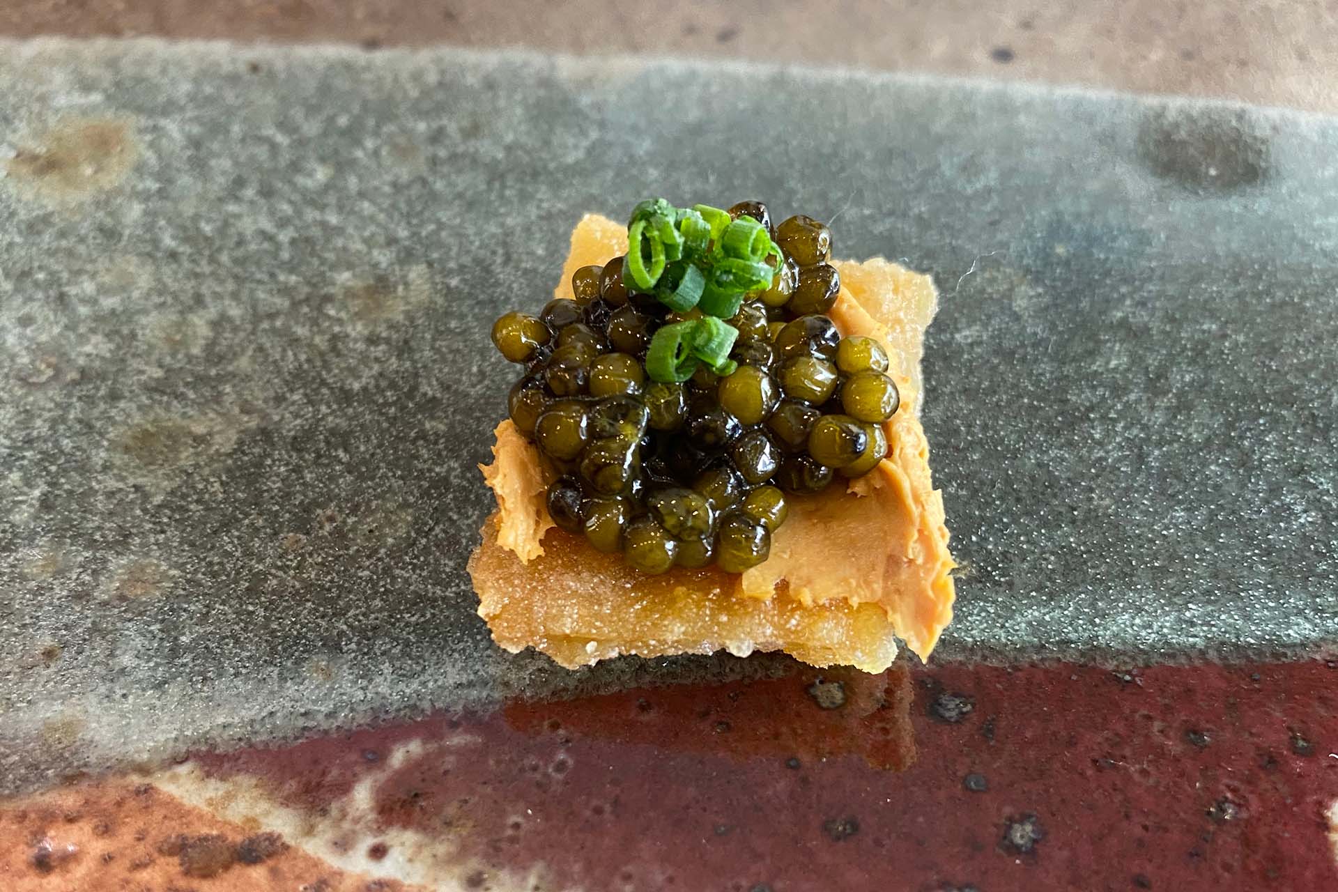 A square of crispy chicken skin topped with caviar.
