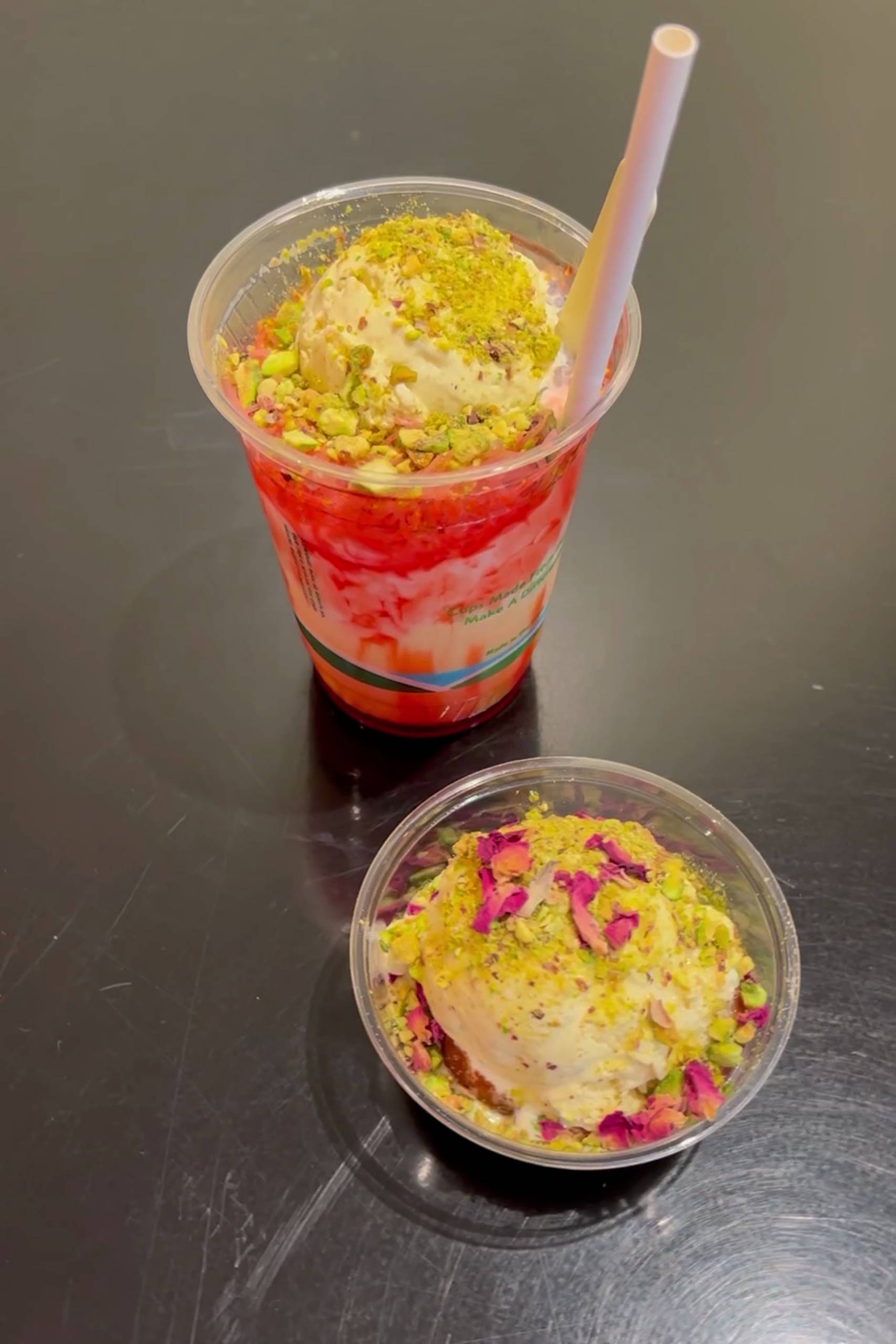 two ice cream-based desserts with Indian toppings and ingredients are displayed on a steel table