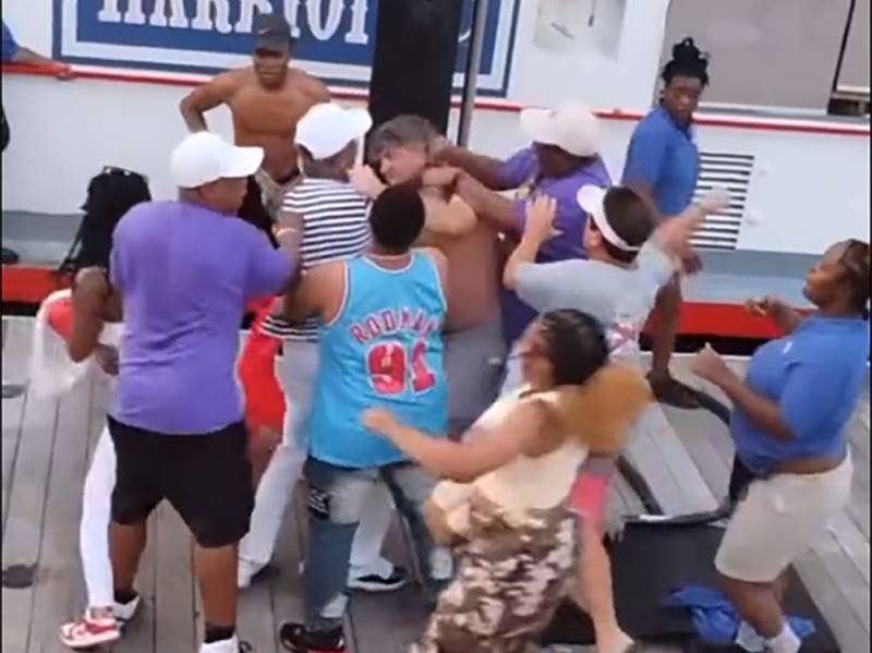 A group of people, both Black and white in a mass brawl next to a docked boat.