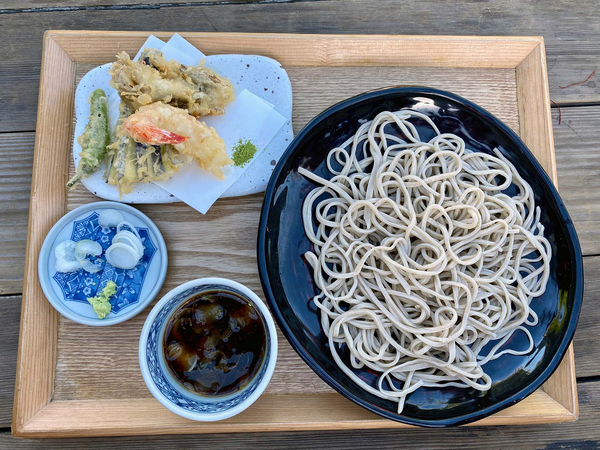A plate of cold soba with dipping sauce and a side of tempura.