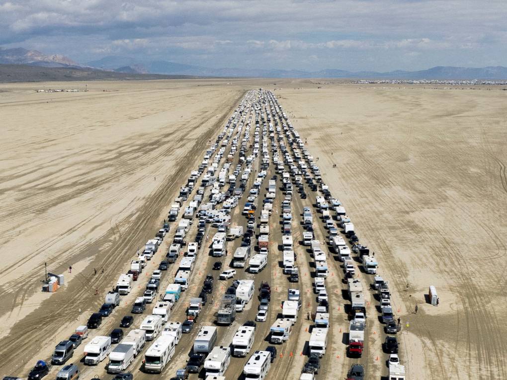 Ten lanes of tightly packed traffic stretch across a dirt path, stretching off into the distance as far as the eye can see.
