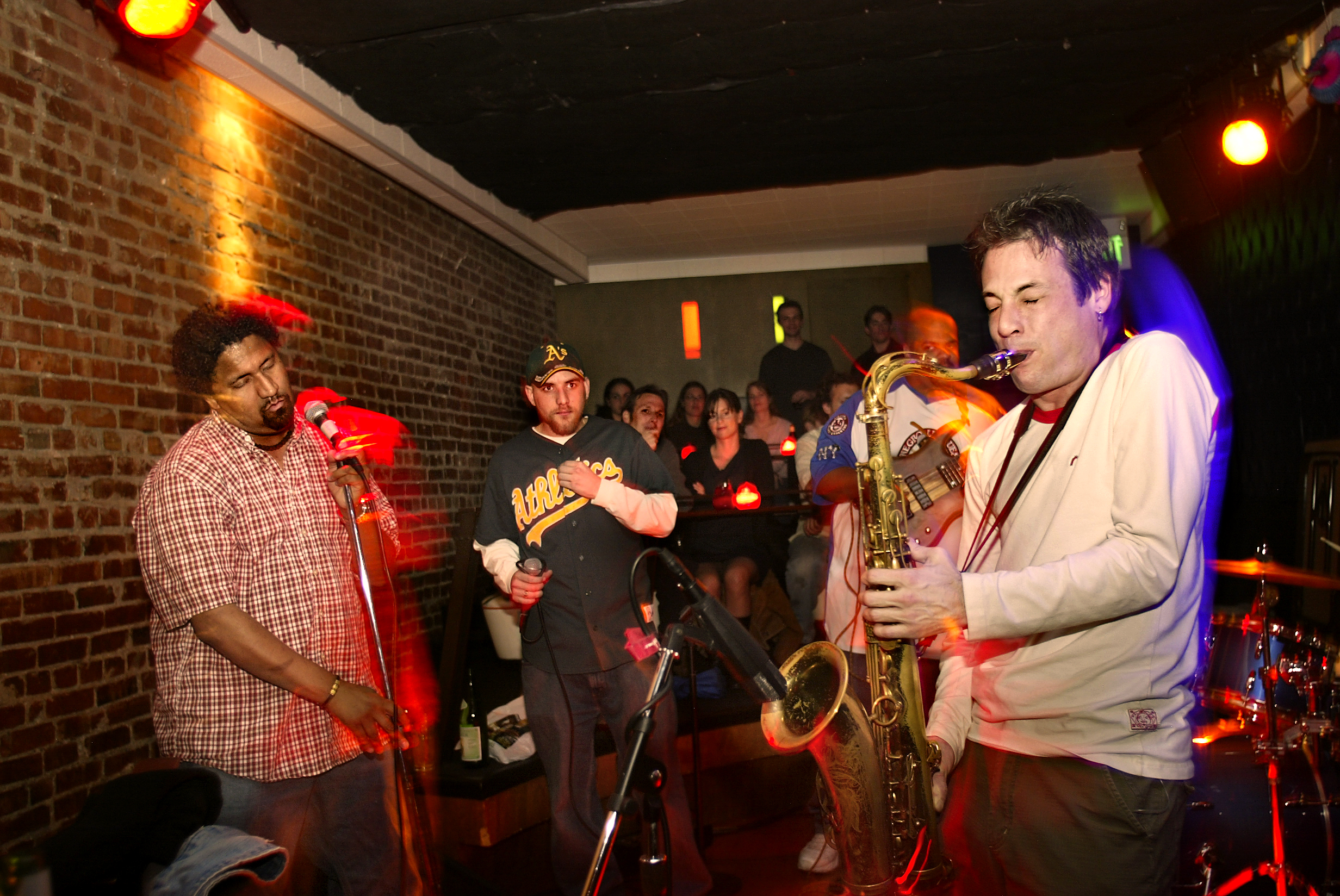 A dynamic performance photo featuring two rappers jamming out with a jazz band.