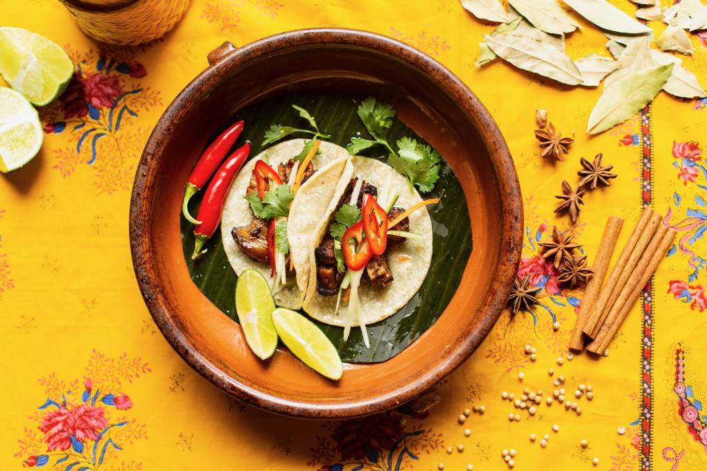 a colorful presentation of Thai-inspired open-faced tacos are plated on a yellow table