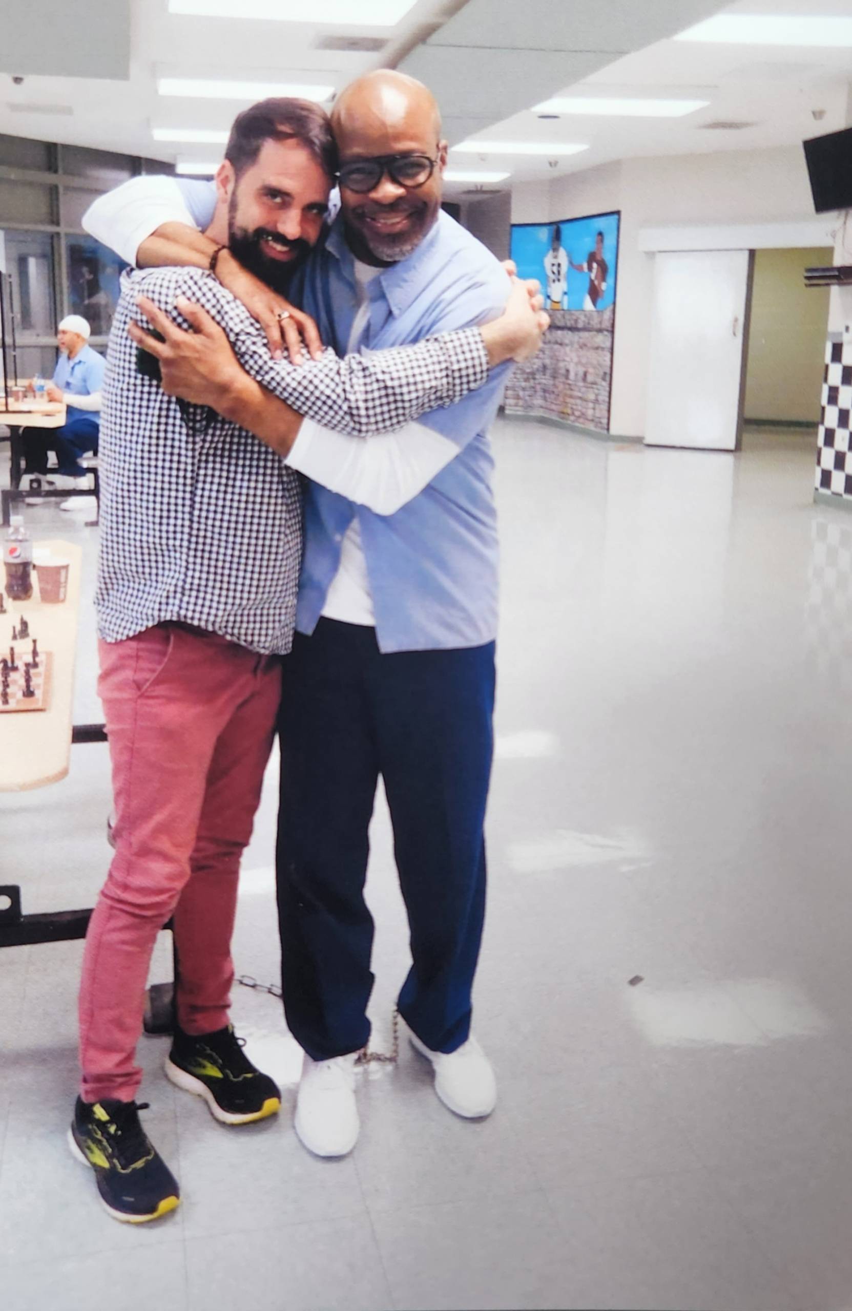 A musician visiting from the outside and an incarcerated poet hug inside a prison.