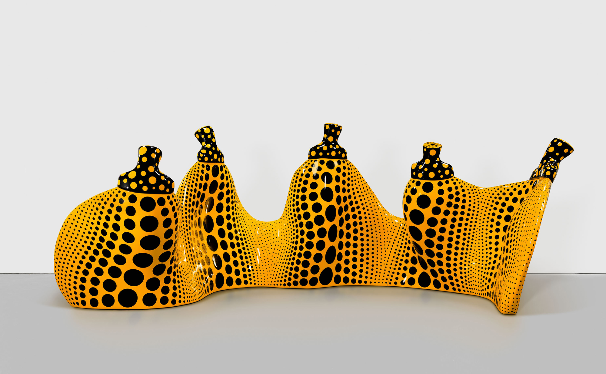 Sculpture of five conjoined pumpkin shapes painted yellow with black dots